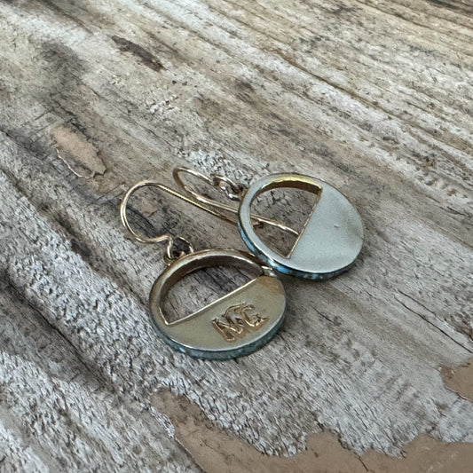 Belle Starr rustic patina earrings with turquoise inlay resting on aged wood, featuring weathered finish and vintage western style
