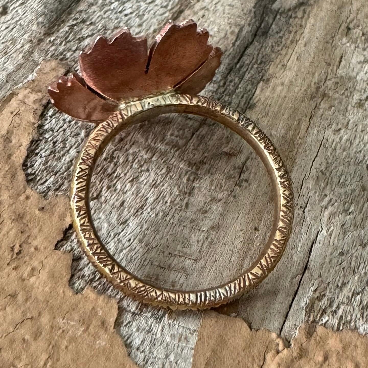 Detail view of copper and sterling silver floret centerpiece with textured brass ring band, rustic handmade ring