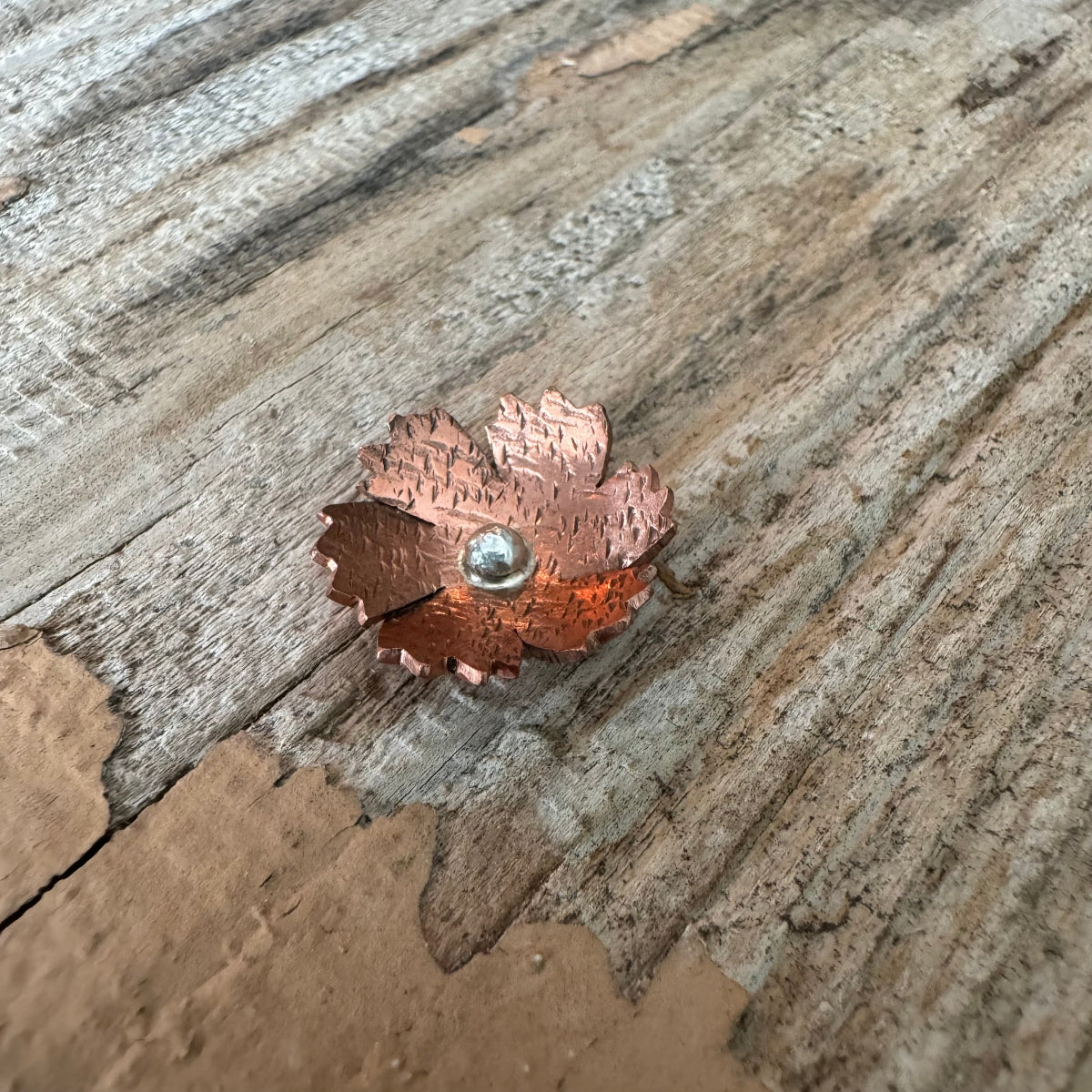 Nelly ring featuring a unique handforged copper and sterling silver floret, resting on rustic wood surface, part of The Floret Collection