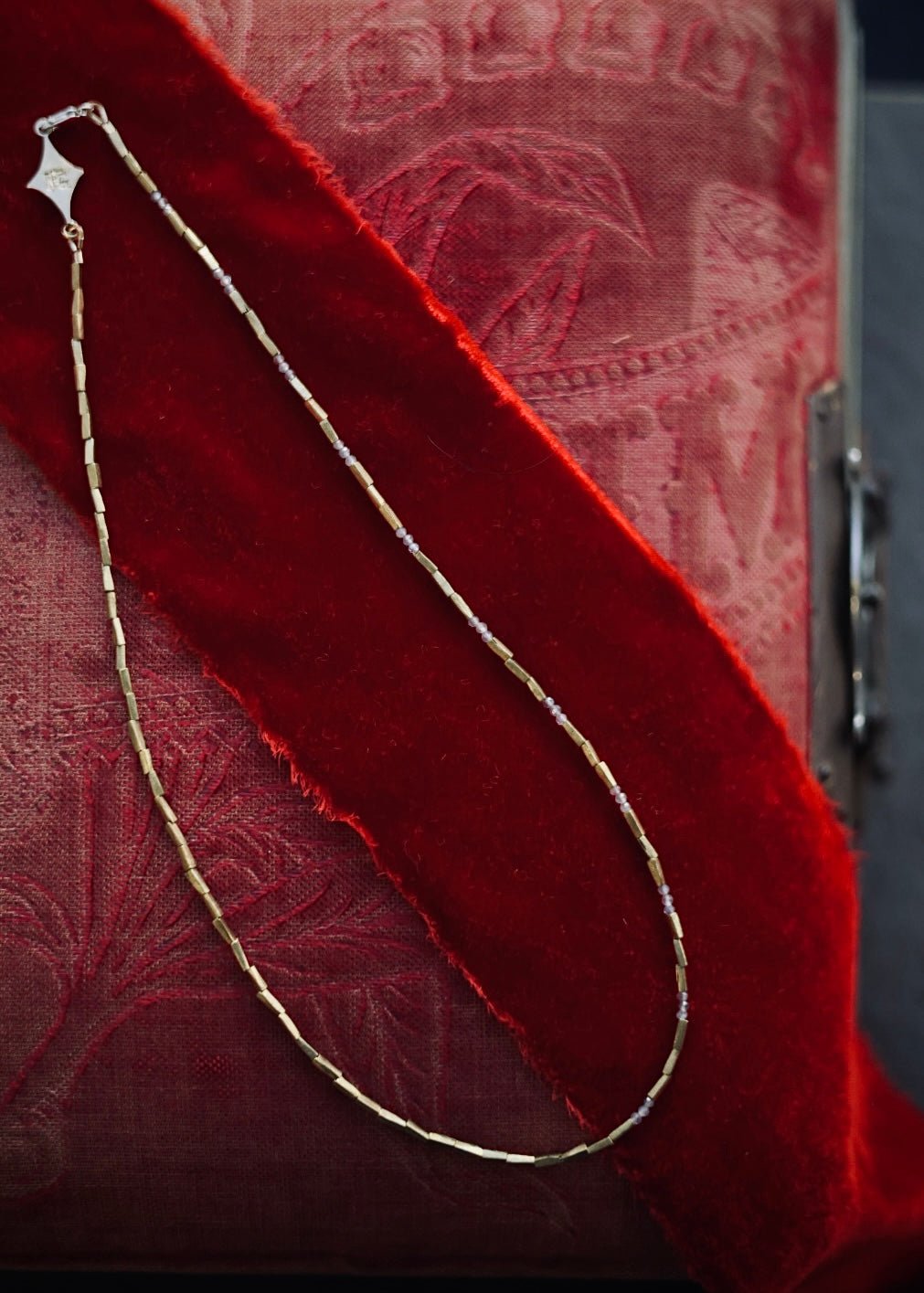 Brass and labradorite necklace draped over a red velvet background