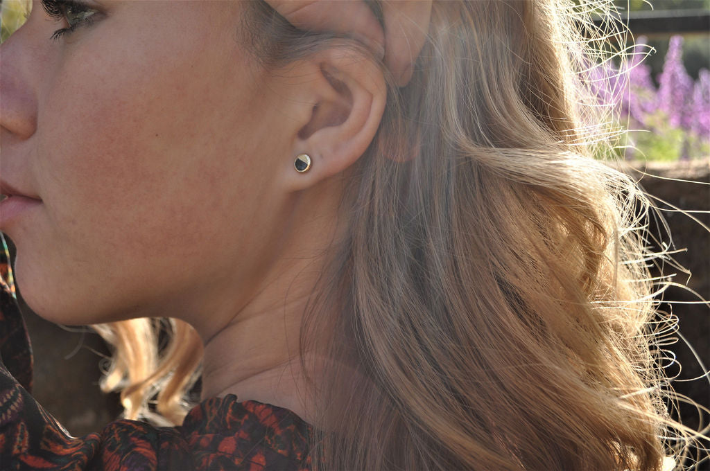 Angled view of the Holliday Black Jade stud earring on a model in floral dress, emphasizing the earring's size and minimal, elegant silhouette.

