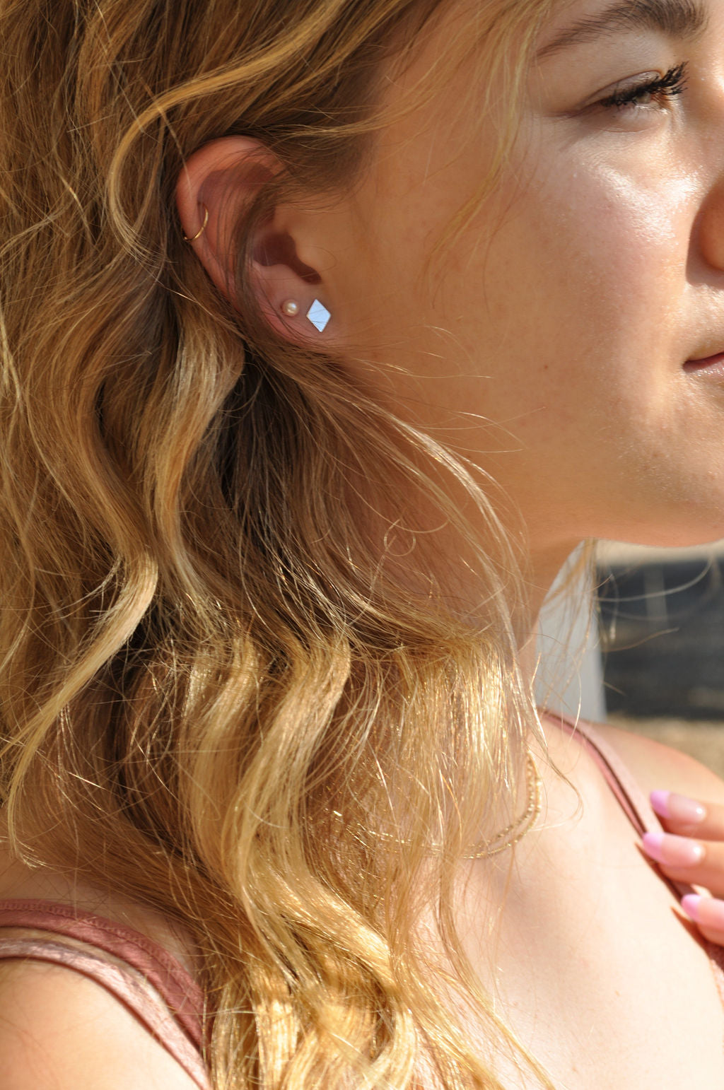 Profile of model wearing a sterling silver Diamond Pharo stud earring paired with a pink top