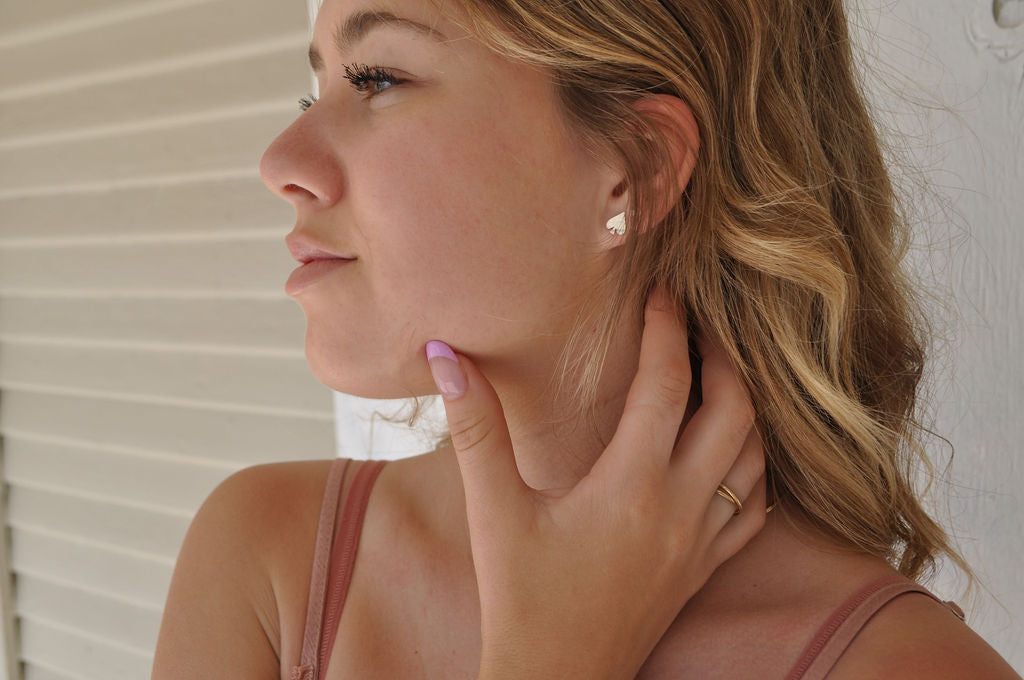 Profile of a model wearing a pharo spade sterling silver earring paired with a pink top.