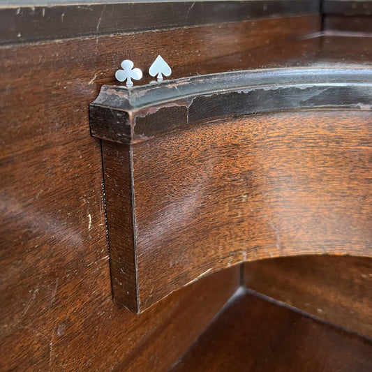 Close-up of Pharo sterling silver stud earrings in the shapes of a club and spade, resting on worn wooden piano surface, highlighting their polished finish and detailed design.